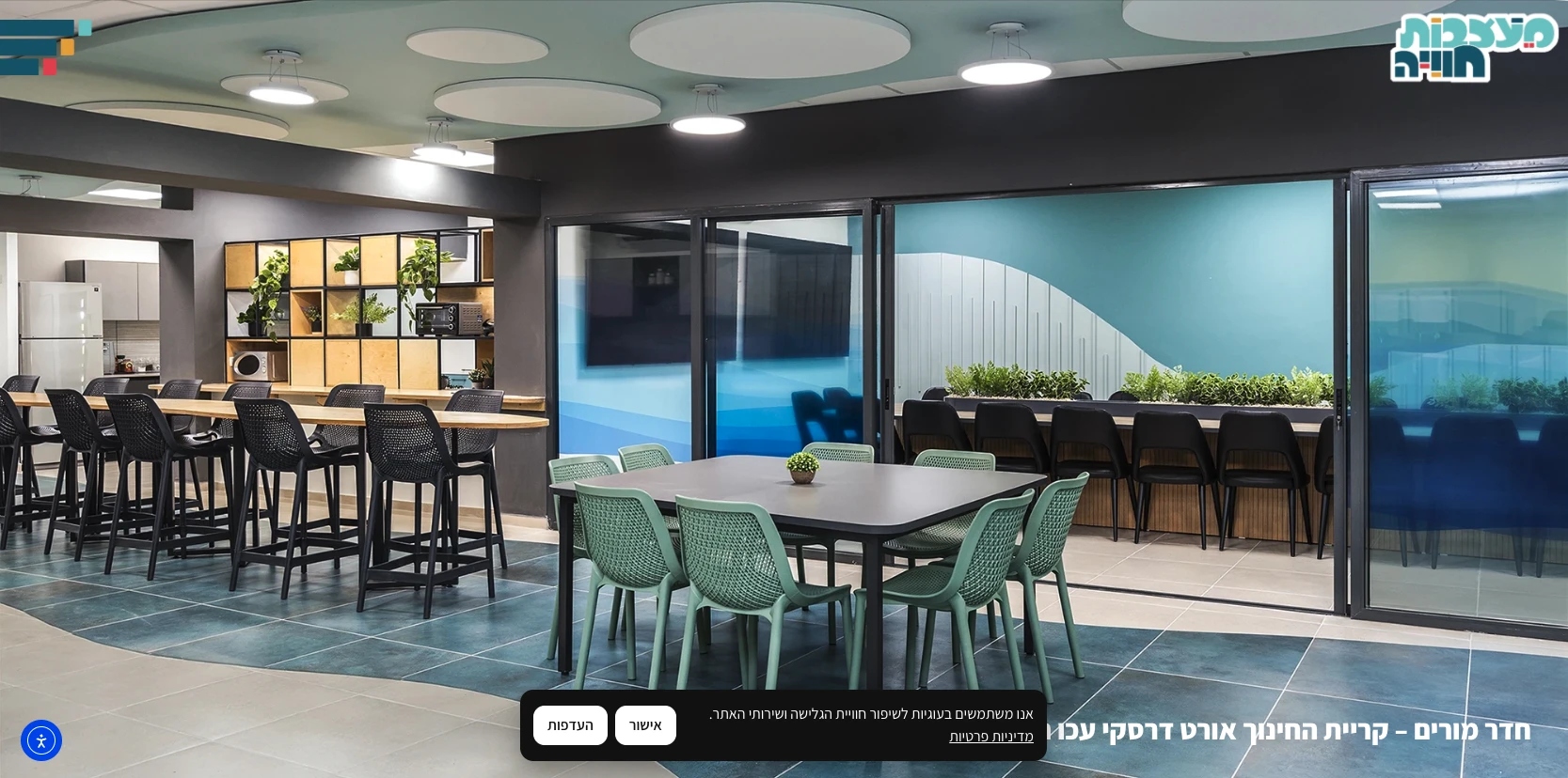 חדר מפגשים עם שולחן ירוק, כיסאות שחורים, מטבח בפינה וחלונות גדולים הפונים לחצר